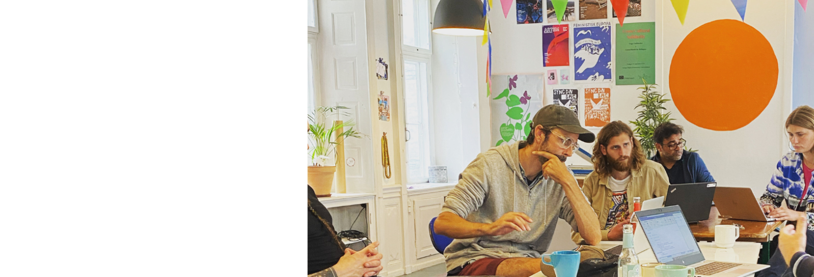 En gruppe personer sidder i møde i farverige omgivelser